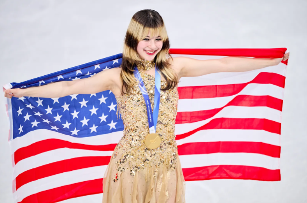 Gold medalist Alysa Liu of Team USA poses with the American flag during the Women’s Singles Figure Skating medal ceremony at the 2026 Winter Olympics in Milan, Italy, on February 19, 2026. The moment celebrates her historic gold-medal victory on Olympic ice. (photo by Vitalii Kliuiev/Getty Images)
